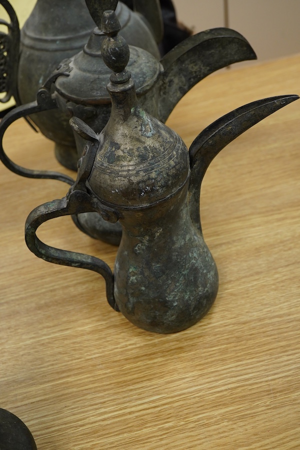 Three Arabic dallahs, two brass, one copper and a copper coffee ewer, 45cm